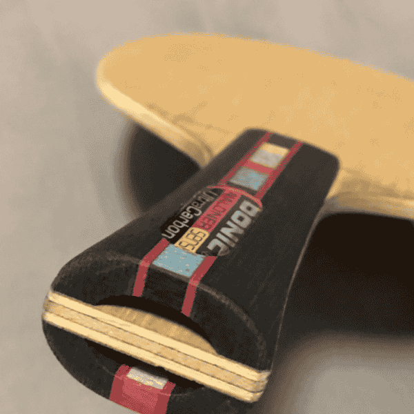 Close-up of a skateboard with a black deck featuring colorful text and graphics.